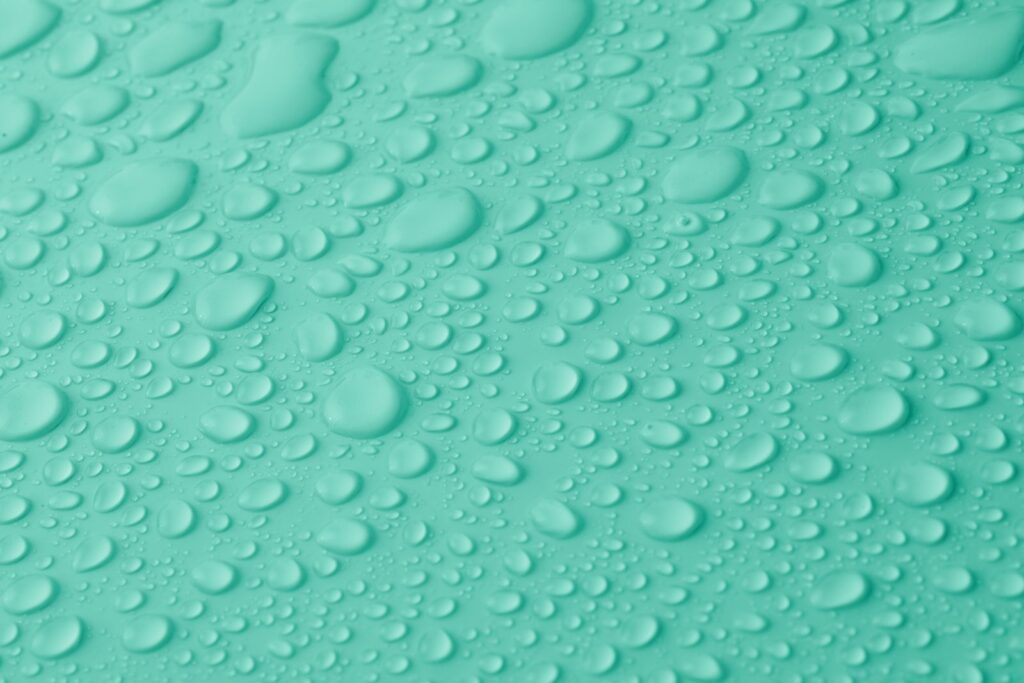 Water droplets on a teal polymer surface