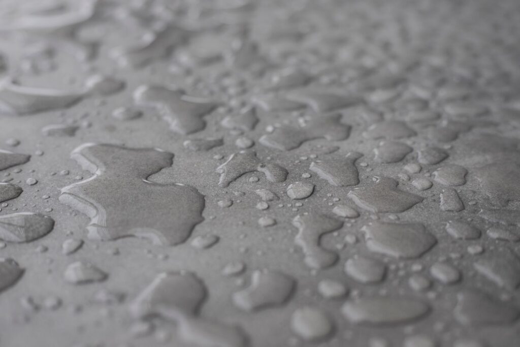 Water drops beading on a light grey sealed surface